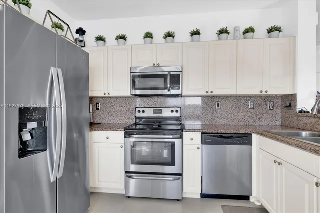 a kitchen with stainless steel appliances white cabinets a stove a sink and a refrigerator