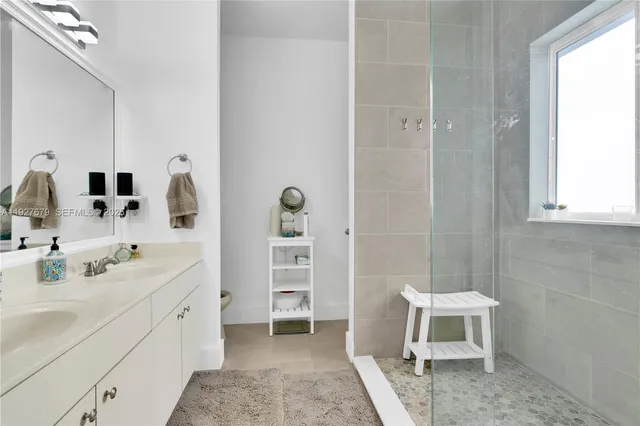 a spacious bathroom with a double vanity sink a toilet and a mirror