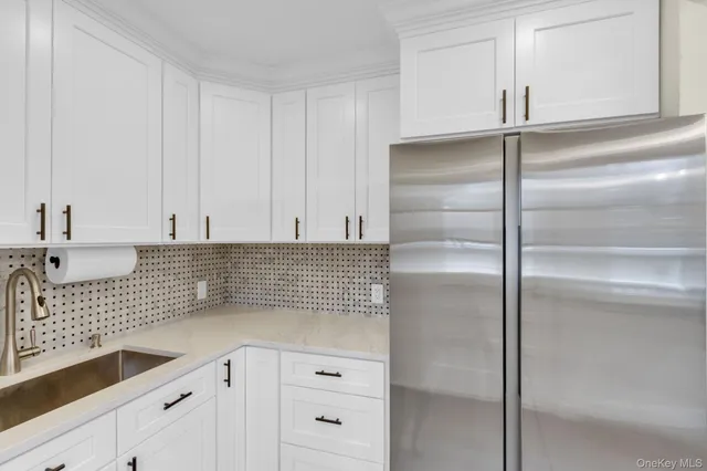 a kitchen with a refrigerator and white cabinets