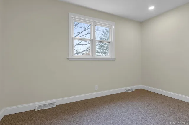 an empty room with a ceiling fan and carpet