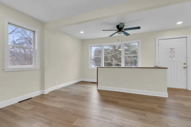 an empty room with wooden floor chandelier fan and windows