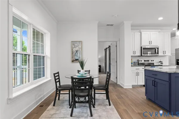 a view of kitchen with stainless steel appliances granite countertop dining table chairs cabinets and a sink