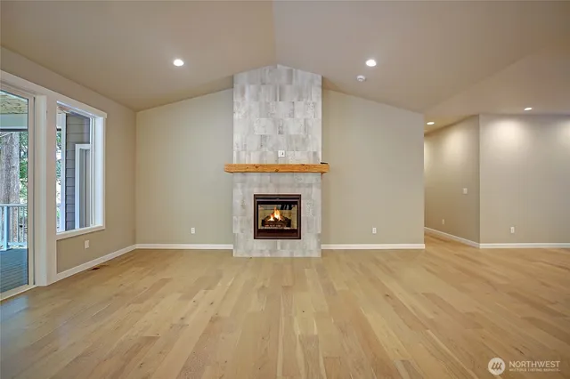 a view of an empty room with wooden floor fireplace and a window