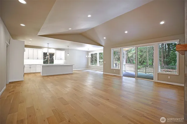an empty room with wooden floor and large windows