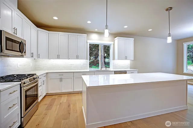 a kitchen with stainless steel appliances granite countertop a sink a stove and a wooden floors