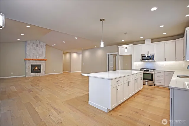 a large kitchen with stainless steel appliances granite countertop a large kitchen island a stove a sink a refrigerator and a fireplace