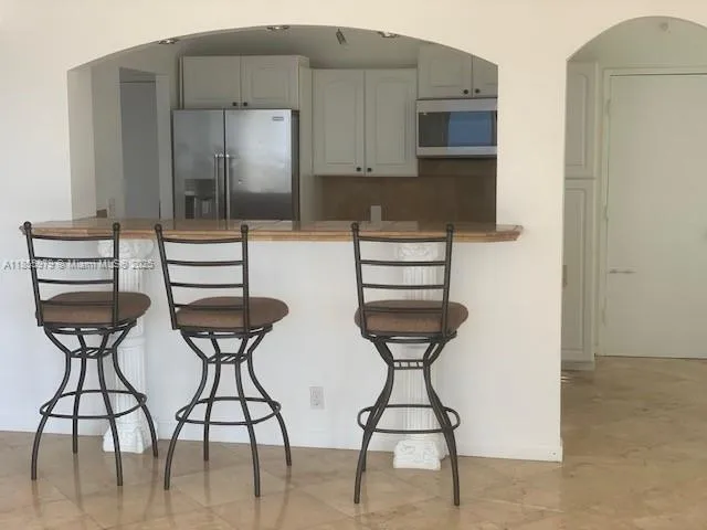 a kitchen with stainless steel appliances kitchen island refrigerator and cabinets