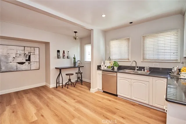 a large white kitchen with wooden floor and a sink