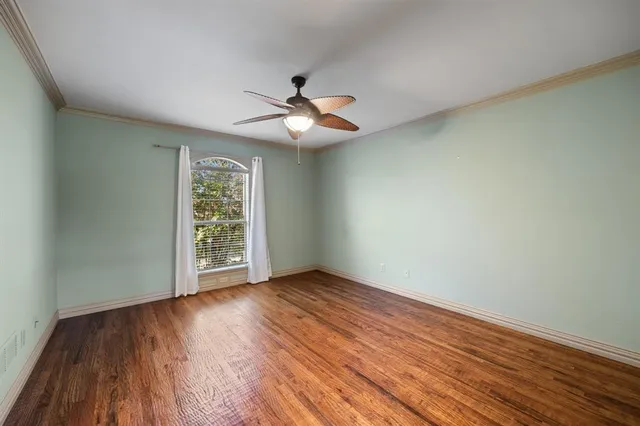 an empty room with wooden floor chandelier fan and windows