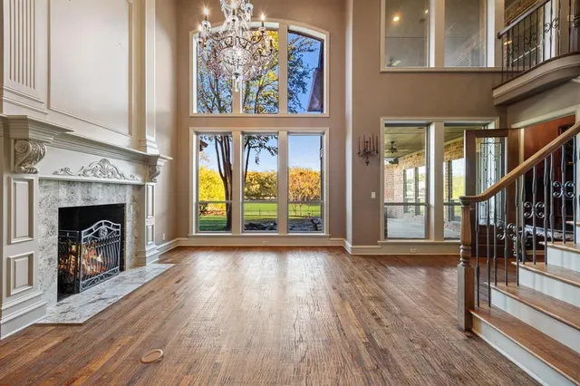 a view of an empty room with wooden floor fireplace and a window