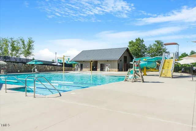 a view of a swimming pool with a patio and a yard
