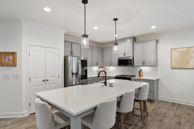 a kitchen with stainless steel appliances a table chairs refrigerator and microwave