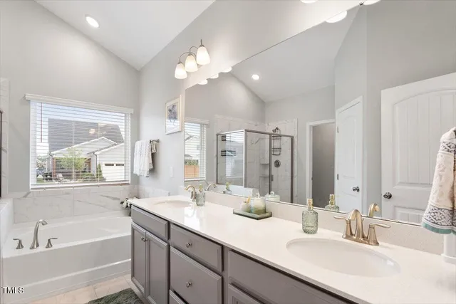 a bathroom with a tub a sink double vanity and a mirror