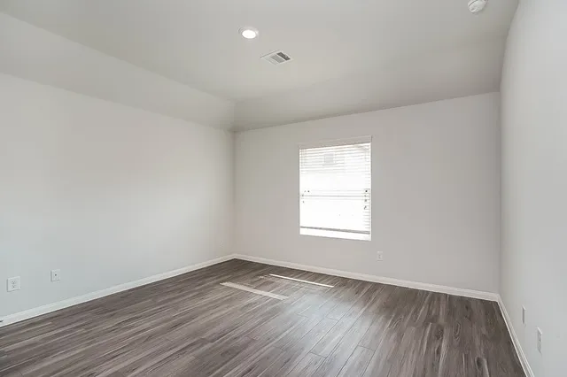 an empty room with wooden floor and window