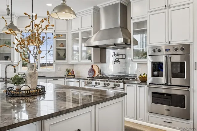 a kitchen with stainless steel appliances granite countertop a sink a stove and a wooden floors