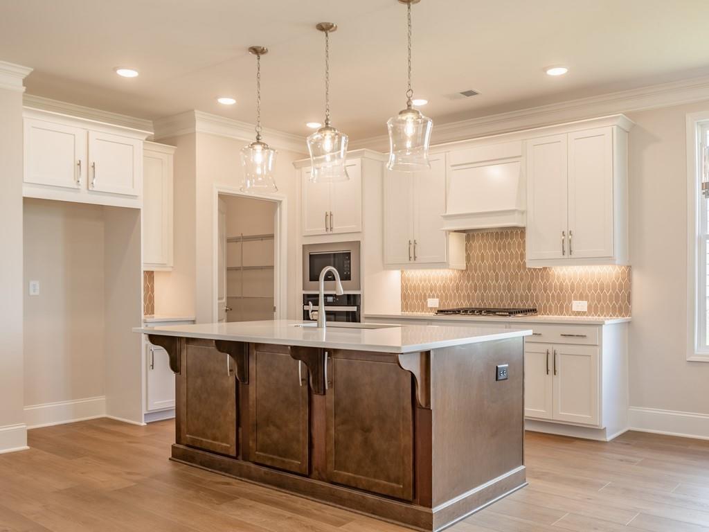a kitchen with stainless steel appliances granite countertop a sink a stove a refrigerator and white cabinets