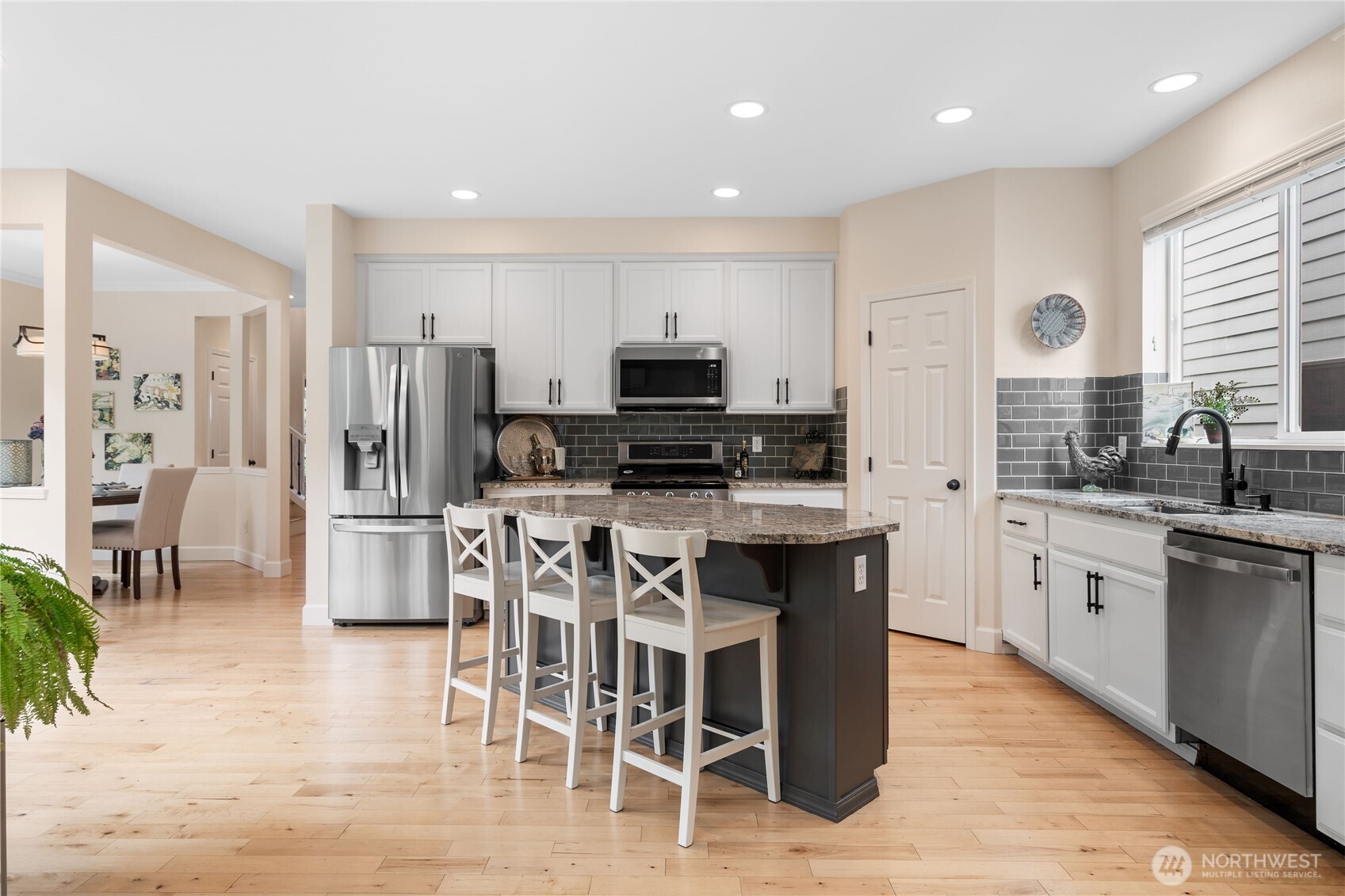 21104 1st Avenue West Bothell, WA 98021 - Photo 11 of 34 a kitchen with stainless steel appliances granite countertop a stove top oven a sink a refrigerator a dining table and chairs