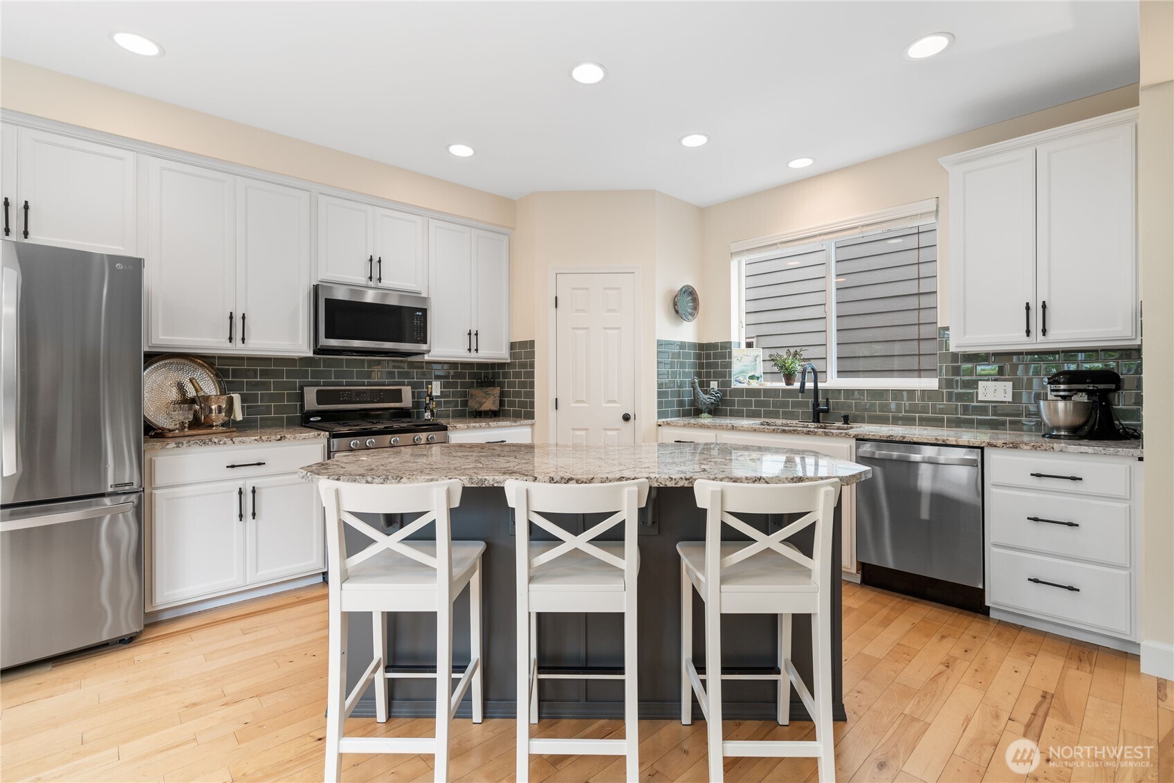 21104 1st Avenue West Bothell, WA 98021 - Photo 12 of 34 a kitchen with stainless steel appliances granite countertop a stove top oven a refrigerator a sink and white cabinets with wooden floor