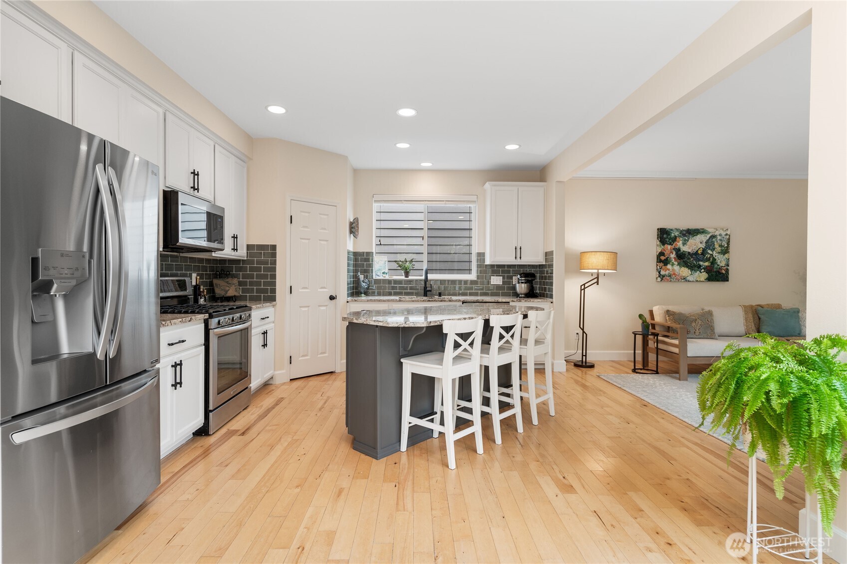 21104 1st Avenue West Bothell, WA 98021 - Photo 10 of 34 a kitchen with stainless steel appliances kitchen island granite countertop a refrigerator a stove a sink a dining table and chairs with wooden floor