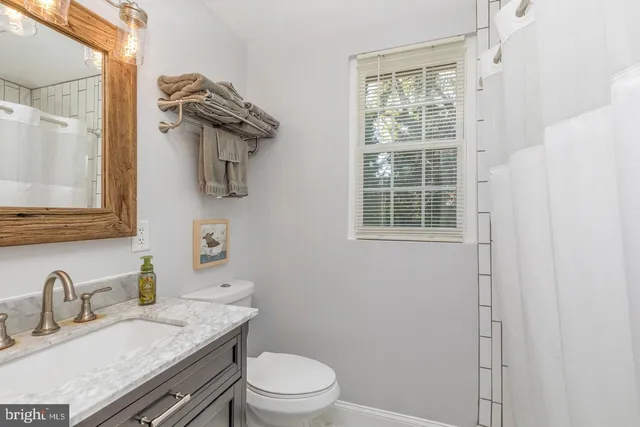a bathroom with a granite countertop sink toilet a mirror and shower