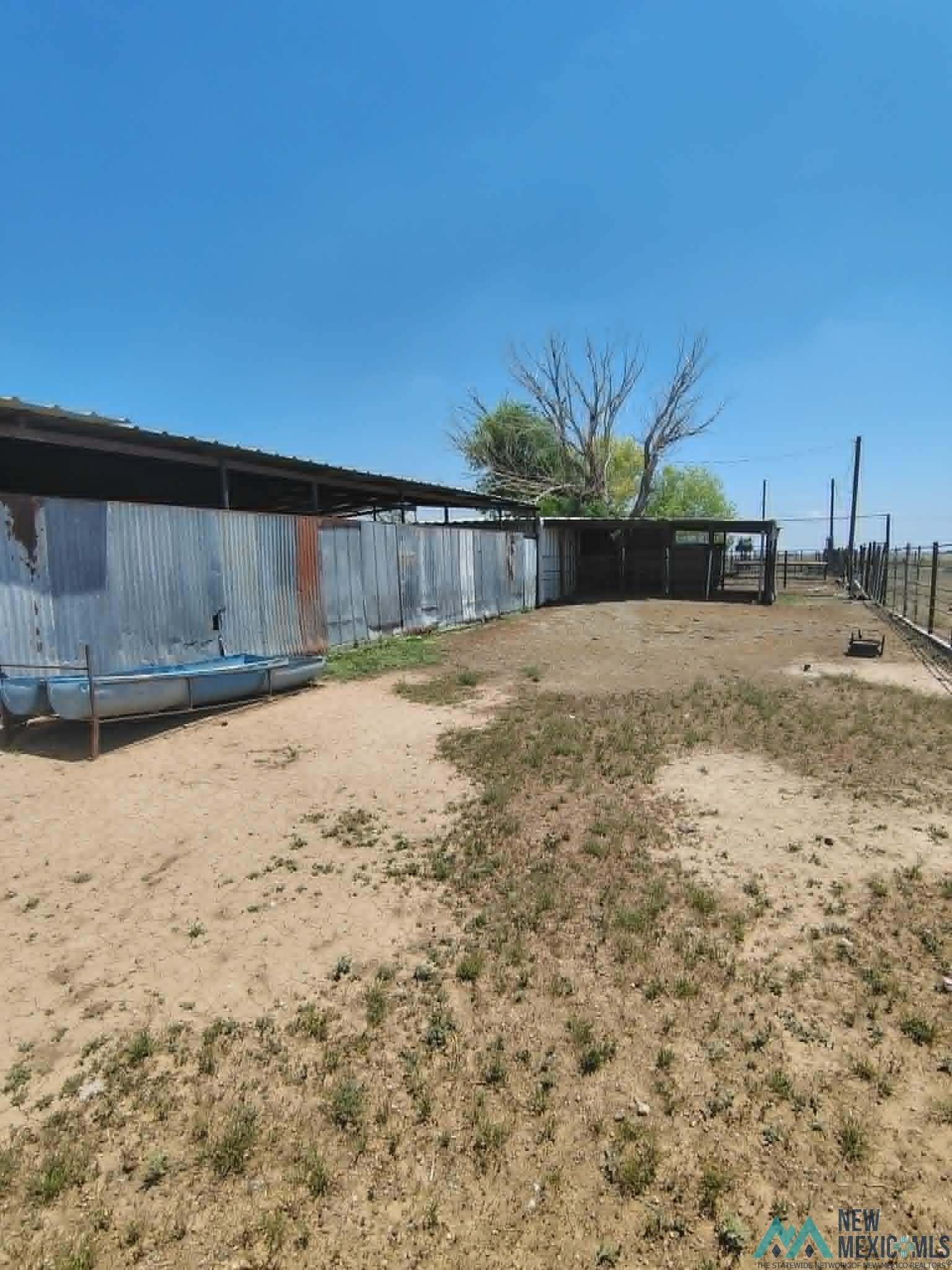 58 Fisk Road Dexter, NM 88230 - Photo 31 of 46 Exterior area featuring a large covered structure with corrugated metal siding, an open-sided shelter, and perimeter fencing