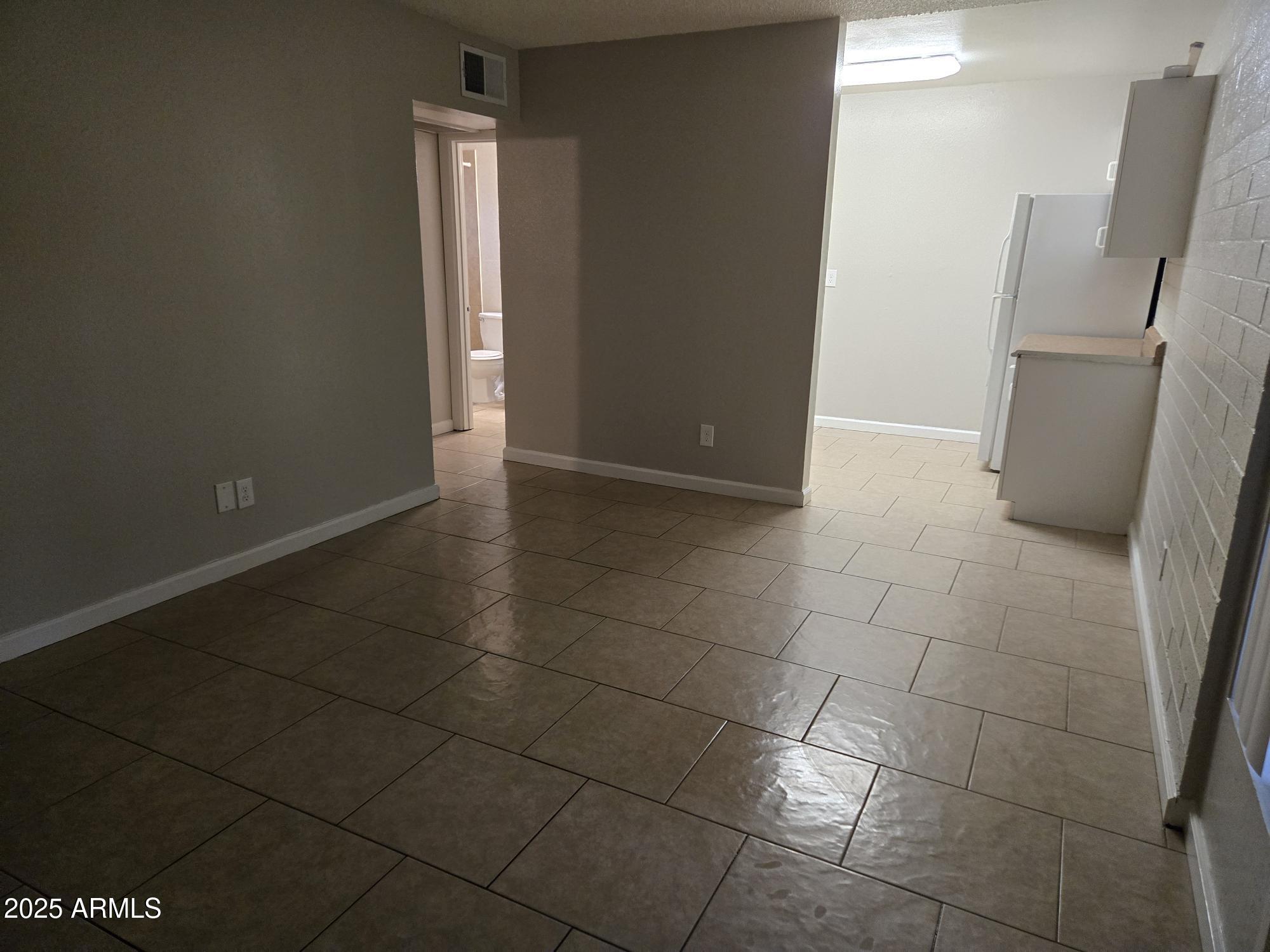 902 East Southern Avenue, Unit 2 Phoenix, AZ 85040 - Photo 2 of 25 a view of a refrigerator in kitchen and an empty room in wooden floor