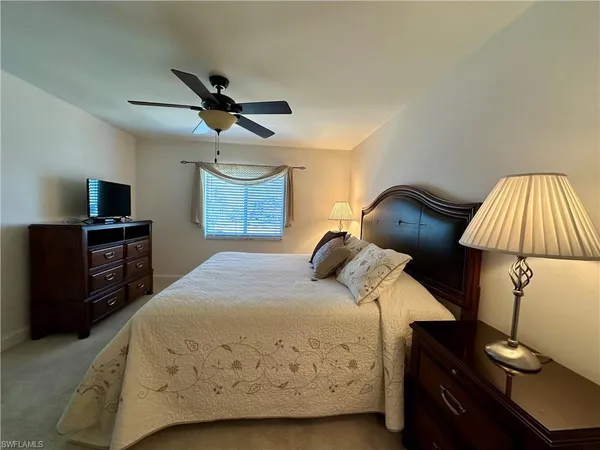 a bedroom with a bed and a flat tv screen on the dresser