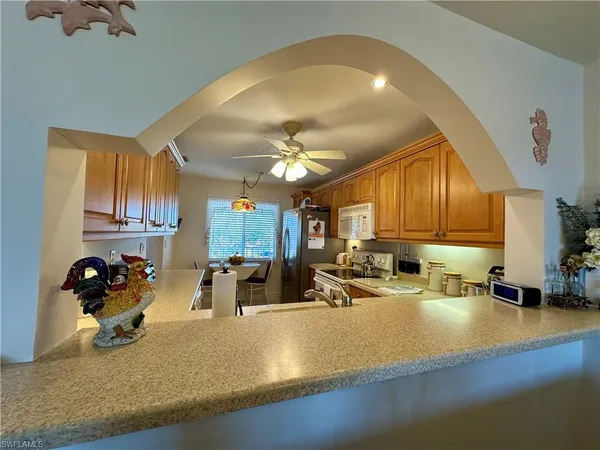 a view of a kitchen with kitchen island a large counter top space a sink stainless steel appliances and cabinets