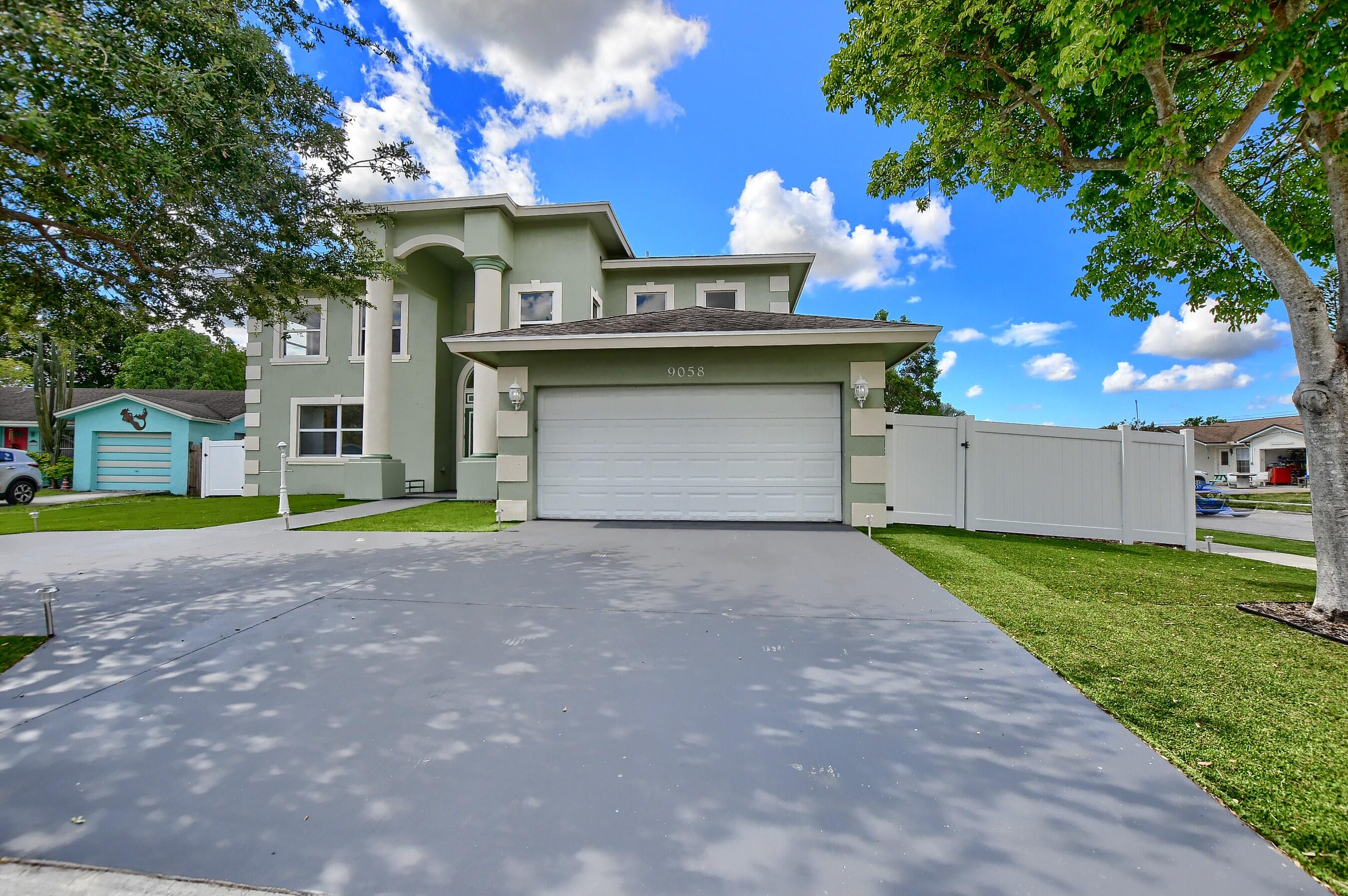 9058 Southwest 4th Street Boca Raton, FL 33433 - Photo 2 of 53 a view of a white house with a yard and garage