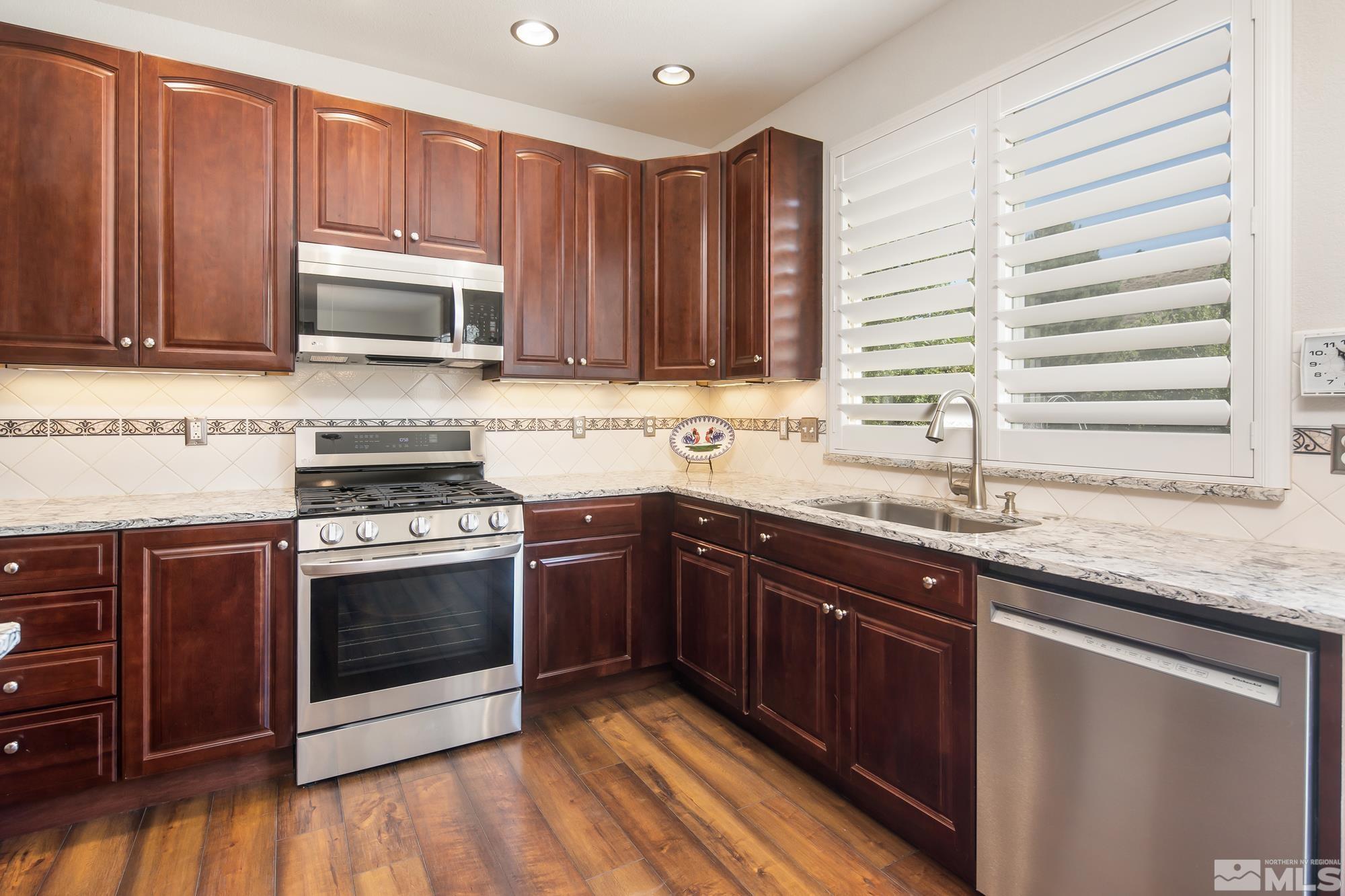5459 Zeppelin Court Reno, NV 89523 - Photo 11 of 36 a kitchen with stainless steel appliances granite countertop a stove a sink and a microwave