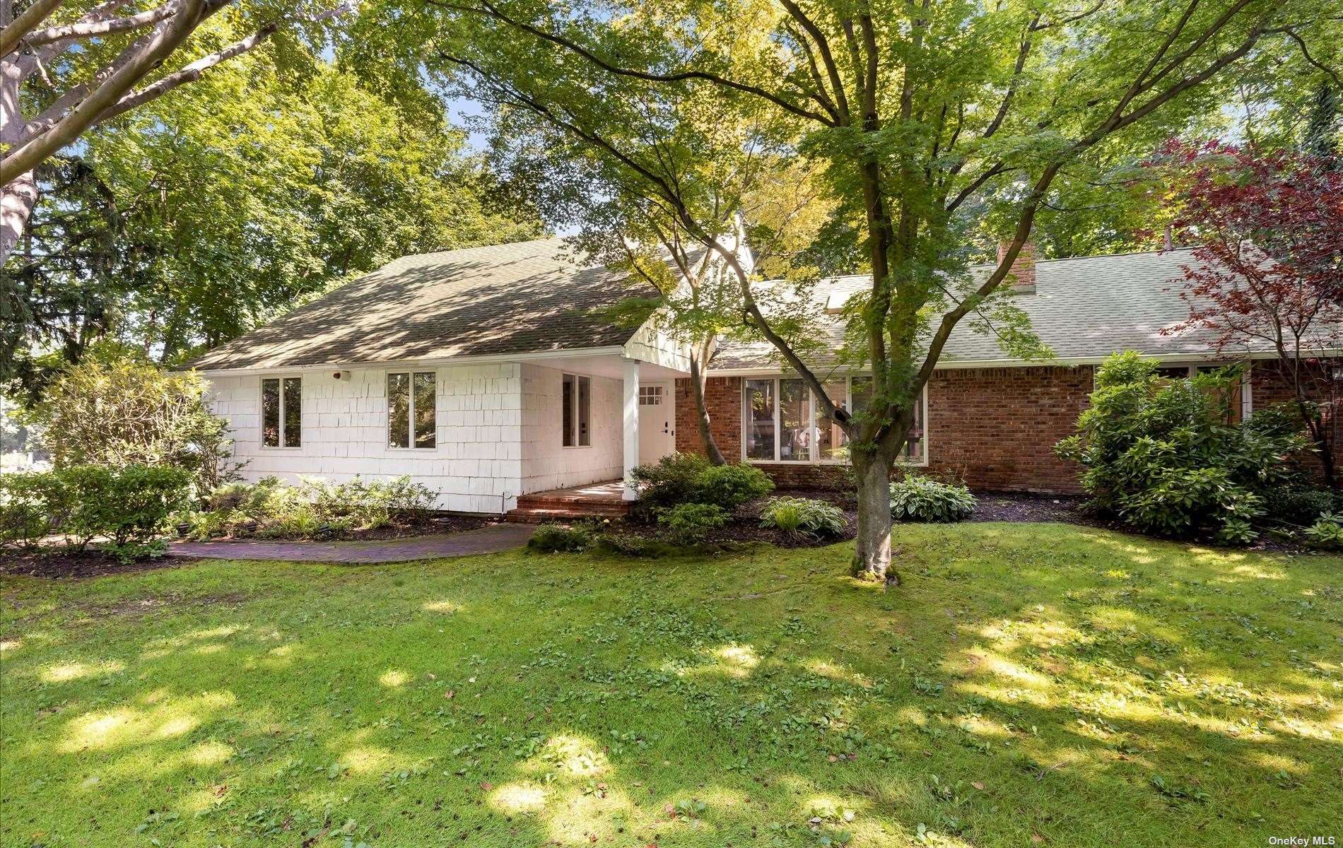 a backyard of a house with plants and large tree