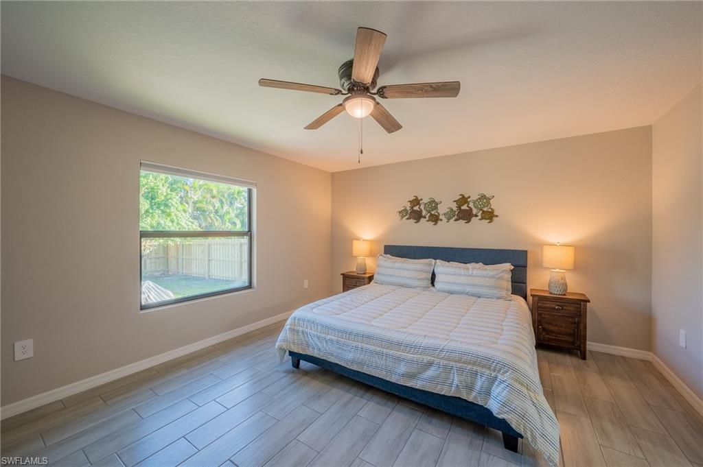 8152 Pelican Road Fort Myers, FL 33967 - Photo 16 of 24 Bedroom featuring wood-finish tile flooring, a window offering exterior sightlines, and a ceiling fan with integrated lighting