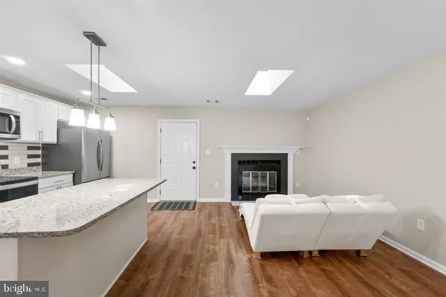 a living room with stainless steel appliances granite countertop furniture and a wooden floor