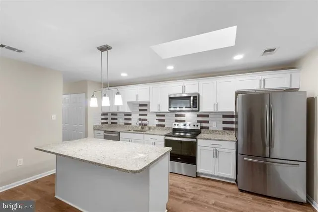 a kitchen with stainless steel appliances a refrigerator a stove a sink and a center island