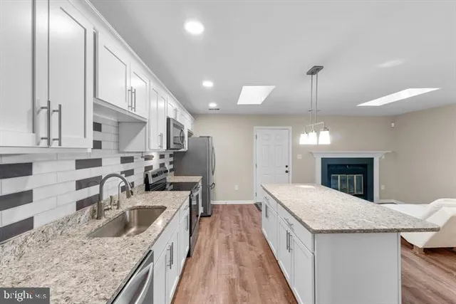 a kitchen with stainless steel appliances granite countertop a sink a stove and a wooden floors