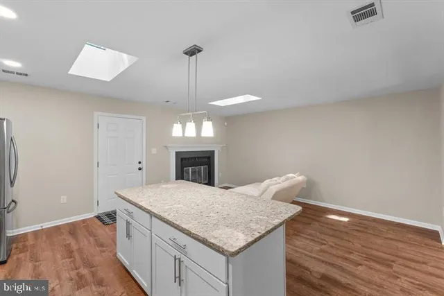 a kitchen with kitchen island stainless steel appliances a sink stove and wooden floor