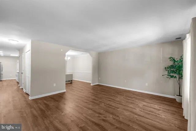 a view of an empty room with wooden floor and a potted plant