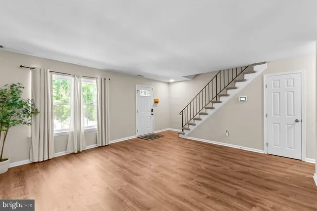 a view of an empty room with wooden floor and entryway