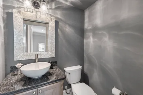 a bathroom with a granite countertop sink a toilet and a mirror