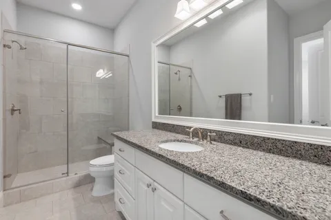a bathroom with a granite countertop sink a toilet and shower