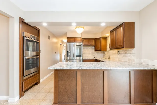 a kitchen with stainless steel appliances granite countertop a sink refrigerator and cabinets