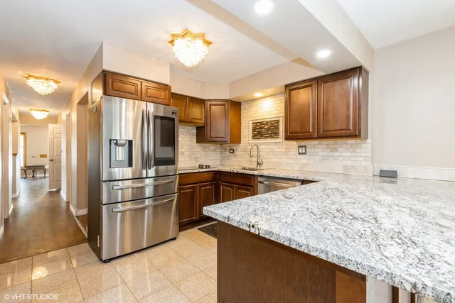 a kitchen with stainless steel appliances granite countertop a refrigerator a stove and a sink