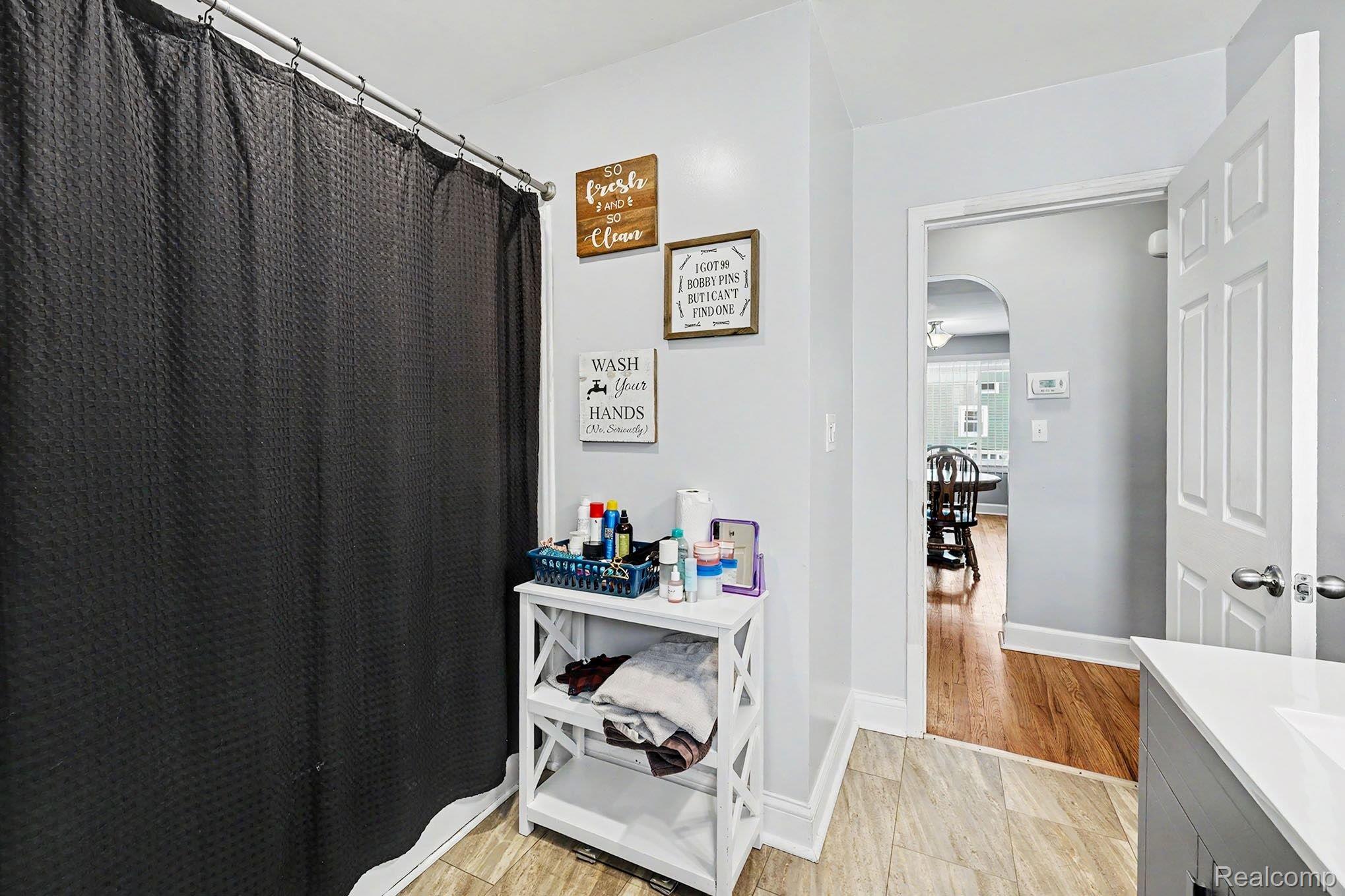 8215 Clinton River Road Sterling Heights, MI 48314 - Photo 13 of 28 Bathroom featuring a shower area with a metal curtain rod, light-toned wall paint, and wood-finish flooring