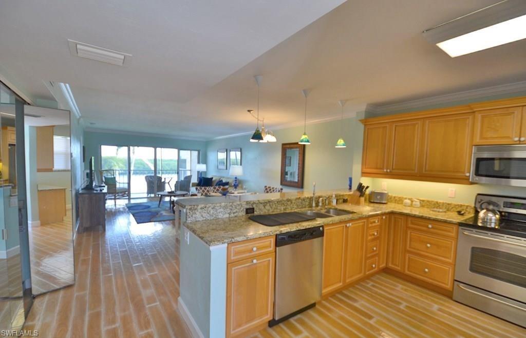 307 Goodlette-Frank Road, Unit 506B Naples, FL 34102 - Photo 10 of 25 a kitchen with a sink stove and wooden cabinets
