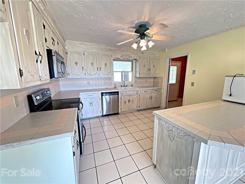 2641 Elbow Road Newton, NC 28658 - Photo 8 of 31 a large kitchen with stainless steel appliances a stove a sink dishwasher and white cabinets with wooden floor
