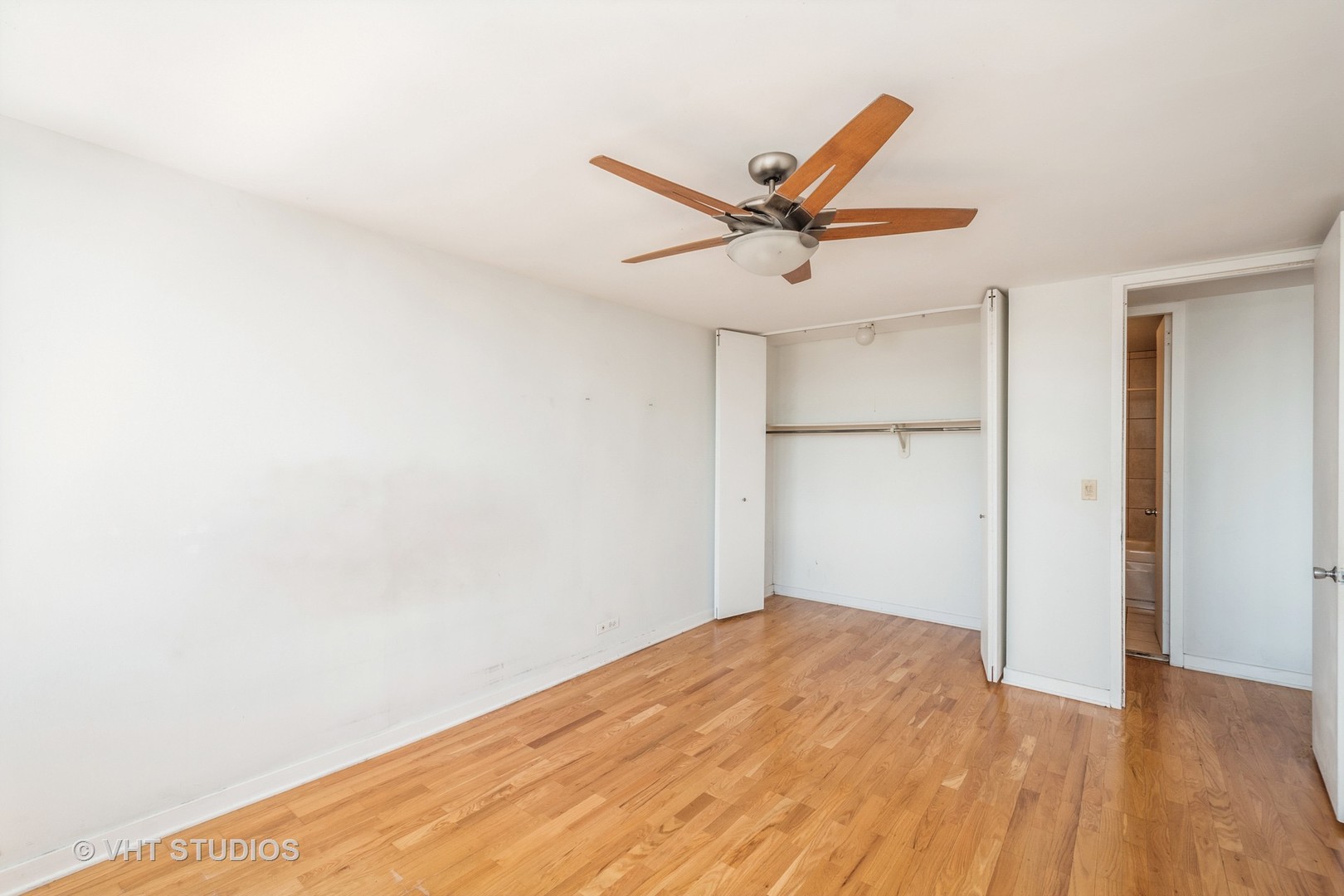655 West Irving Park Road, Unit 4915 Chicago, IL 60613 - Photo 10 of 17 a view of a big room with wooden floor and a ceiling fan