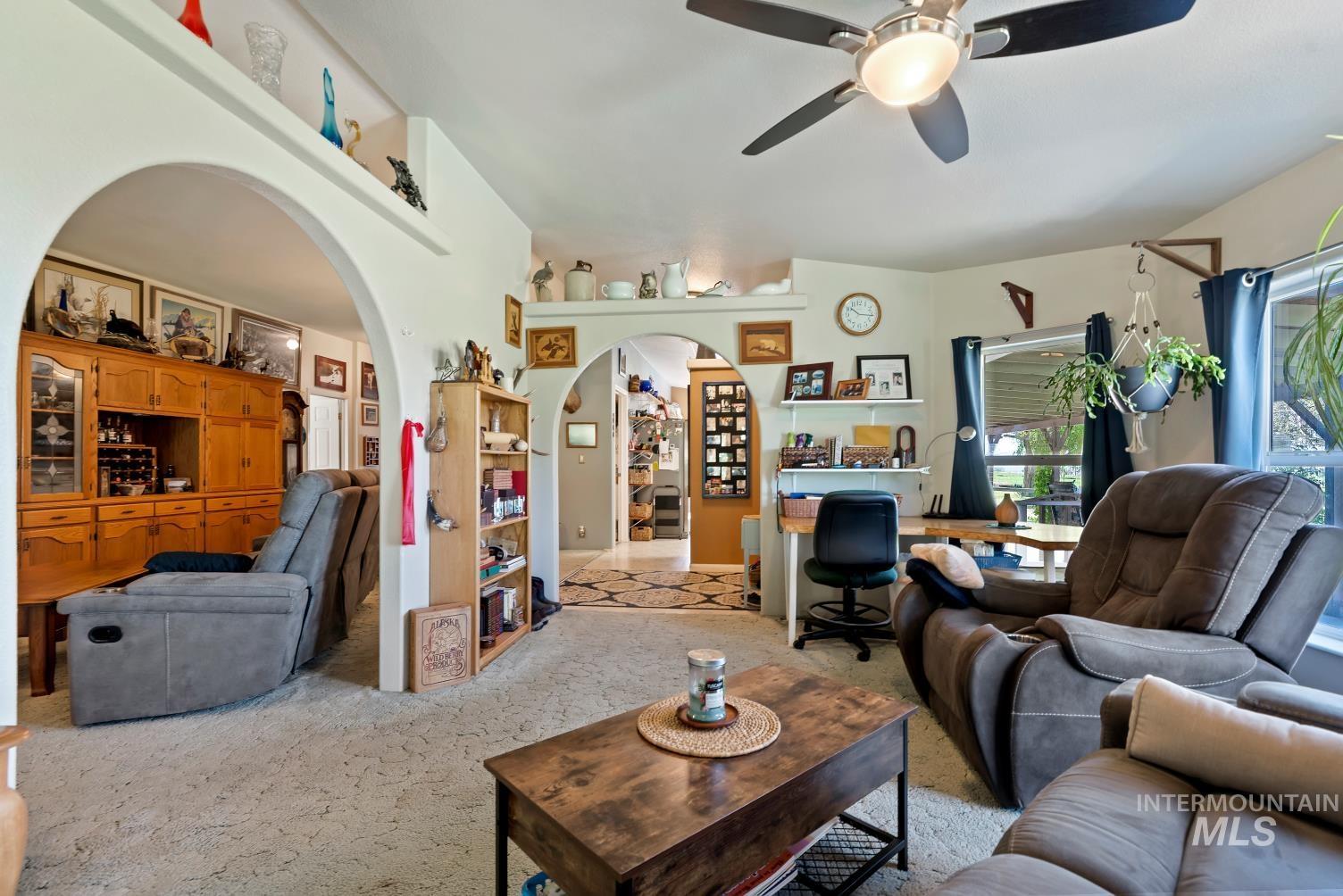 19152 Marsing Road Caldwell, ID 83607 - Photo 15 of 47 Carpeted living area featuring a ceiling fan, arched doorways, a built-in desk area, and natural light from exterior windows