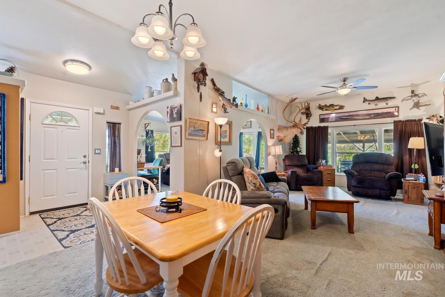 19152 Marsing Road Caldwell, ID 83607 - Photo 18 of 47 Open concept living area featuring a dining space with a chandelier, archway details, and a living room with a ceiling fan
