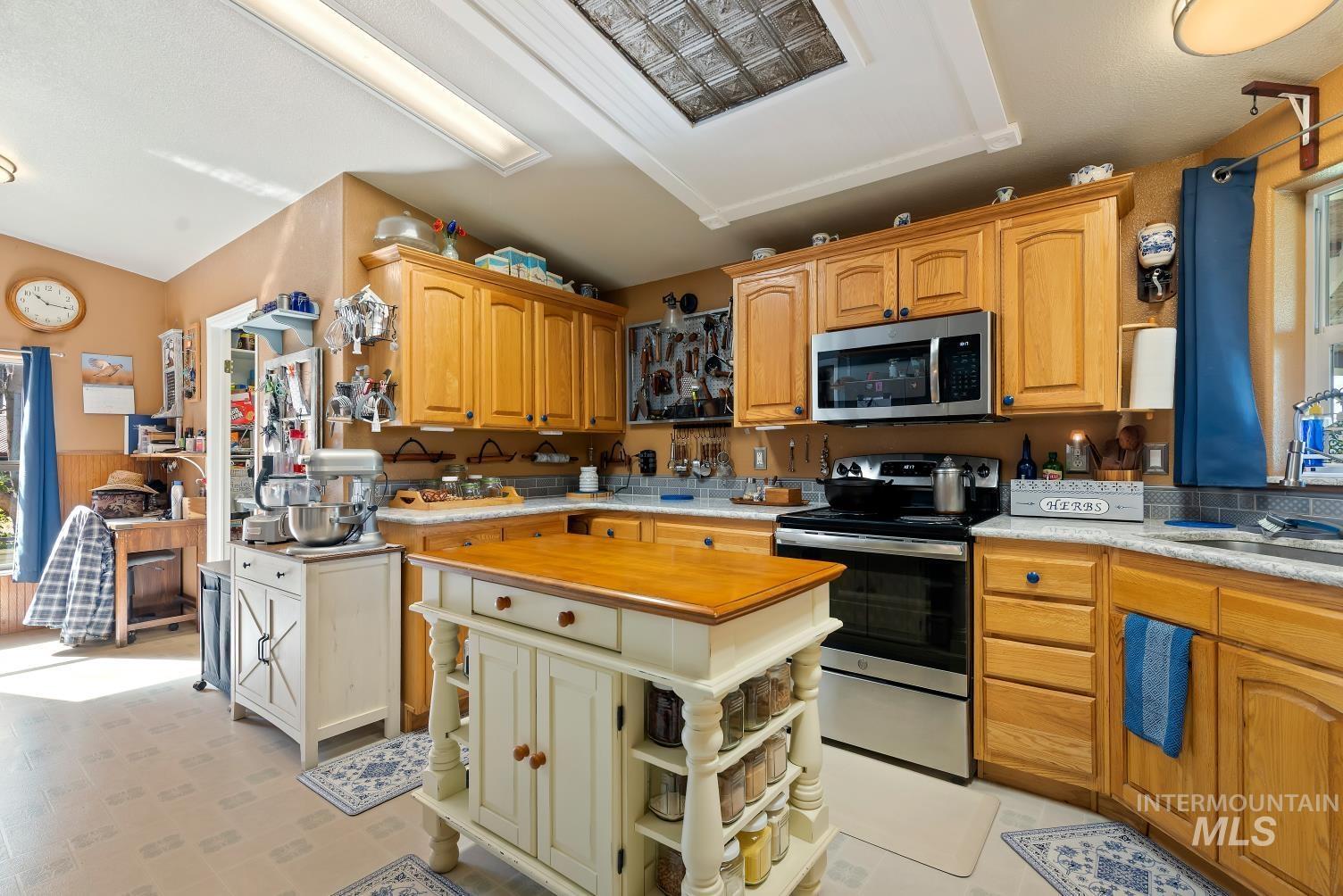 19152 Marsing Road Caldwell, ID 83607 - Photo 19 of 47 Spacious kitchen featuring wood cabinetry, stainless steel appliances, a center island with a wood-finish countertop, and a tiled backsplash