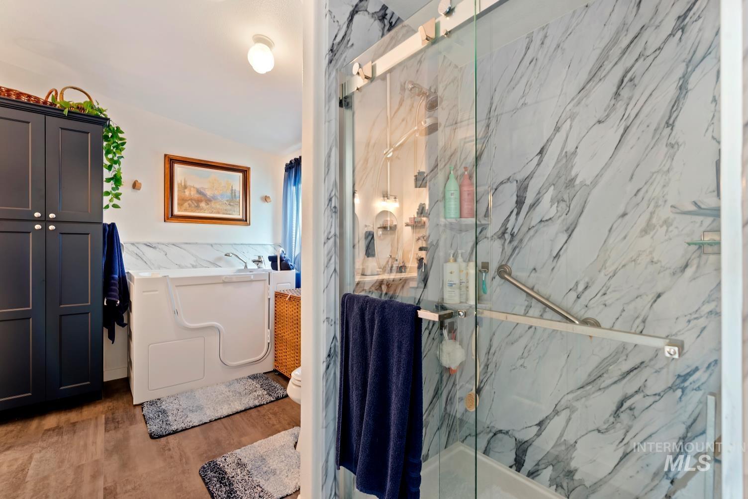 19152 Marsing Road Caldwell, ID 83607 - Photo 27 of 47 Bathroom featuring a glass-enclosed shower with marble-look wall tiling and a built-in grab bar